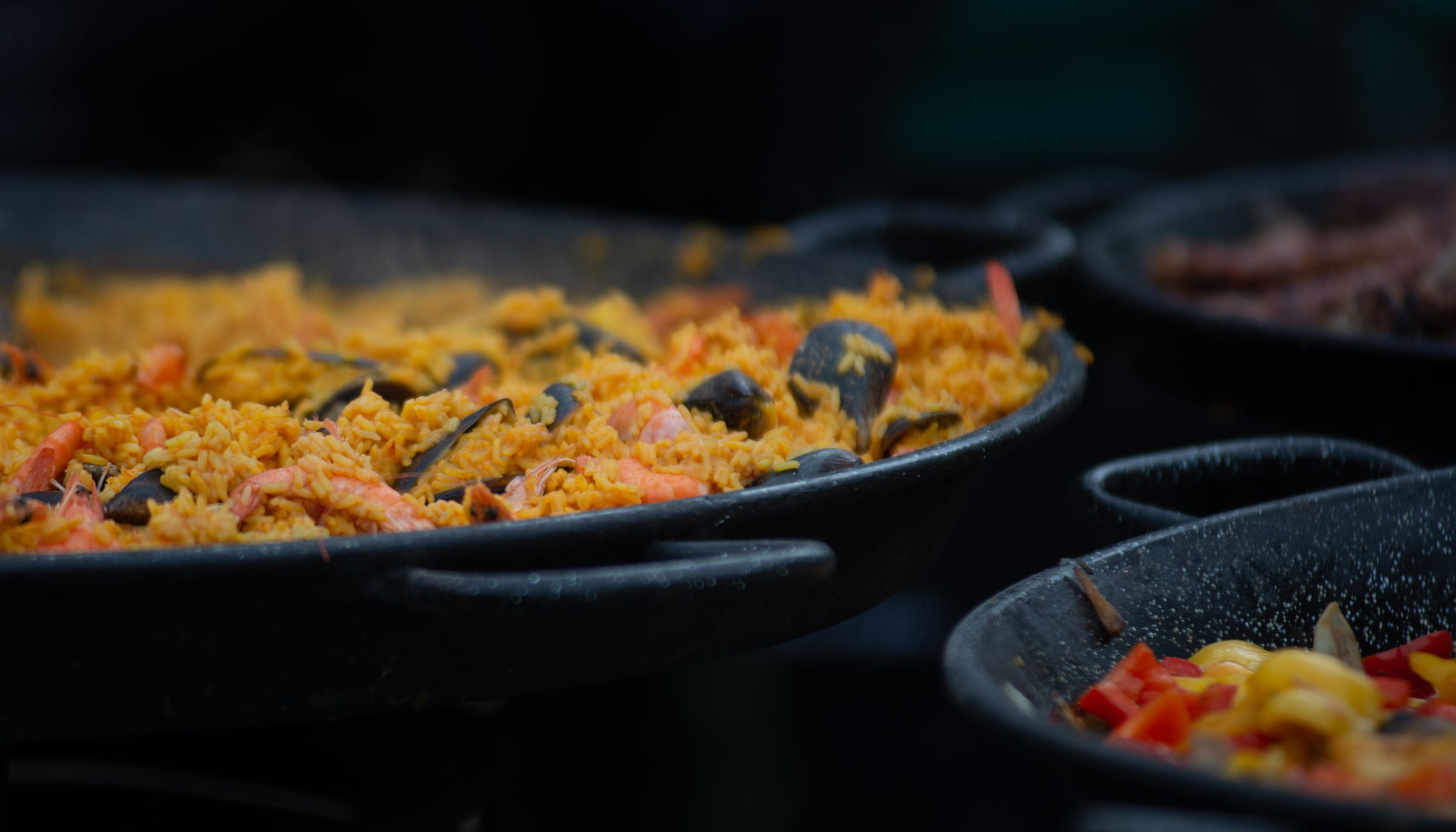 Spanish rice cooking in wide pans with prawns and mussels