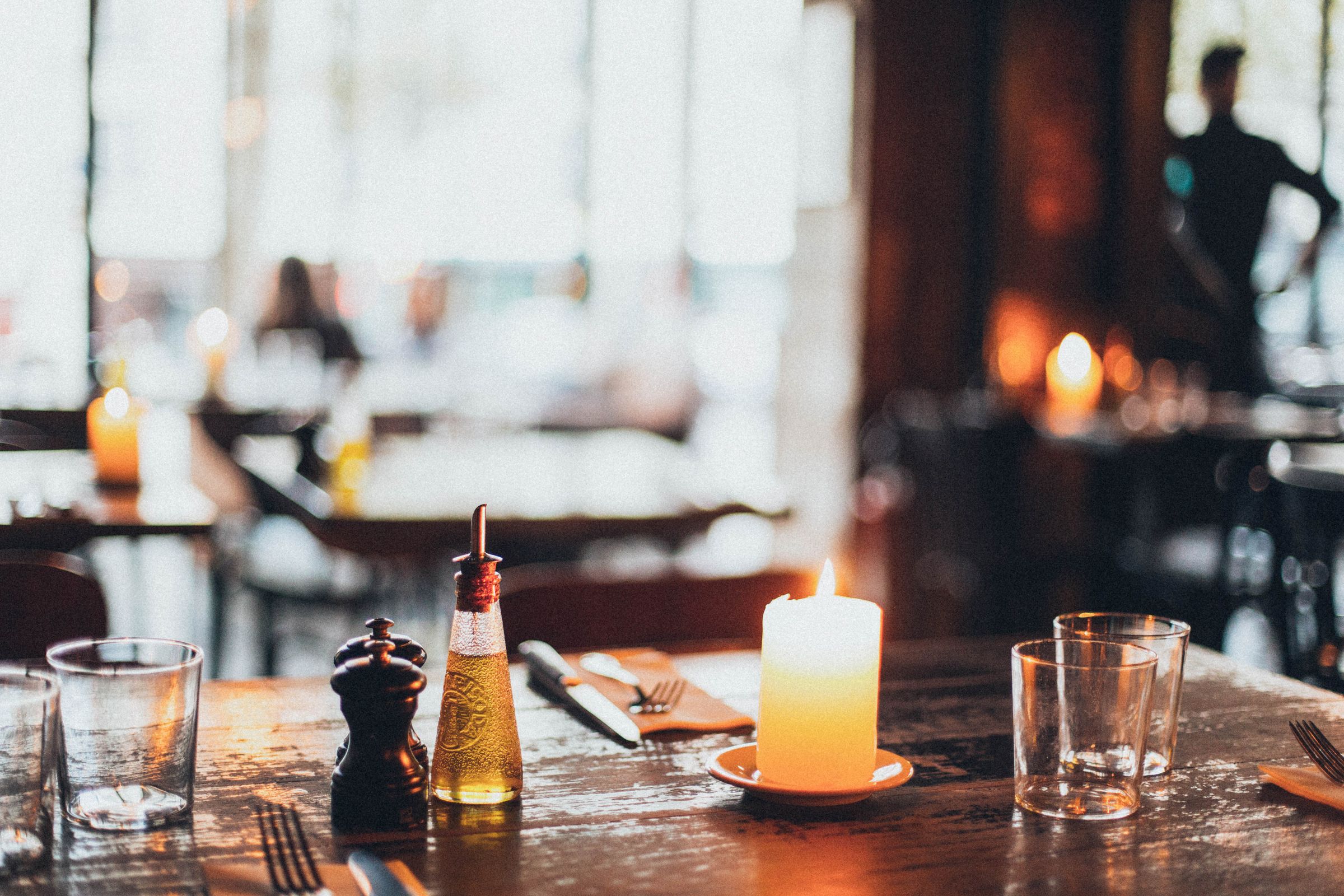 A warm restaurant table at dusk, candle and olive oil